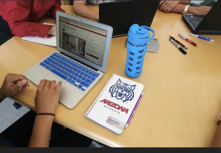 Arizona Wildcat notebook sits next to a laptop and blue water bottle